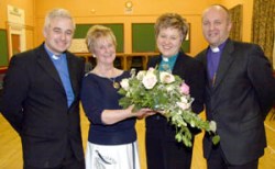 Irene Bell (St Colman’s MU Branch Leader) presents a welcome gift to the new rector of Dunmurry Parish, the Rev Denise Acheson.  Looking on is the Rev Don Gamble (left) and the Bishop of Connor, the Rt Rev Alan Abernethy (right).
